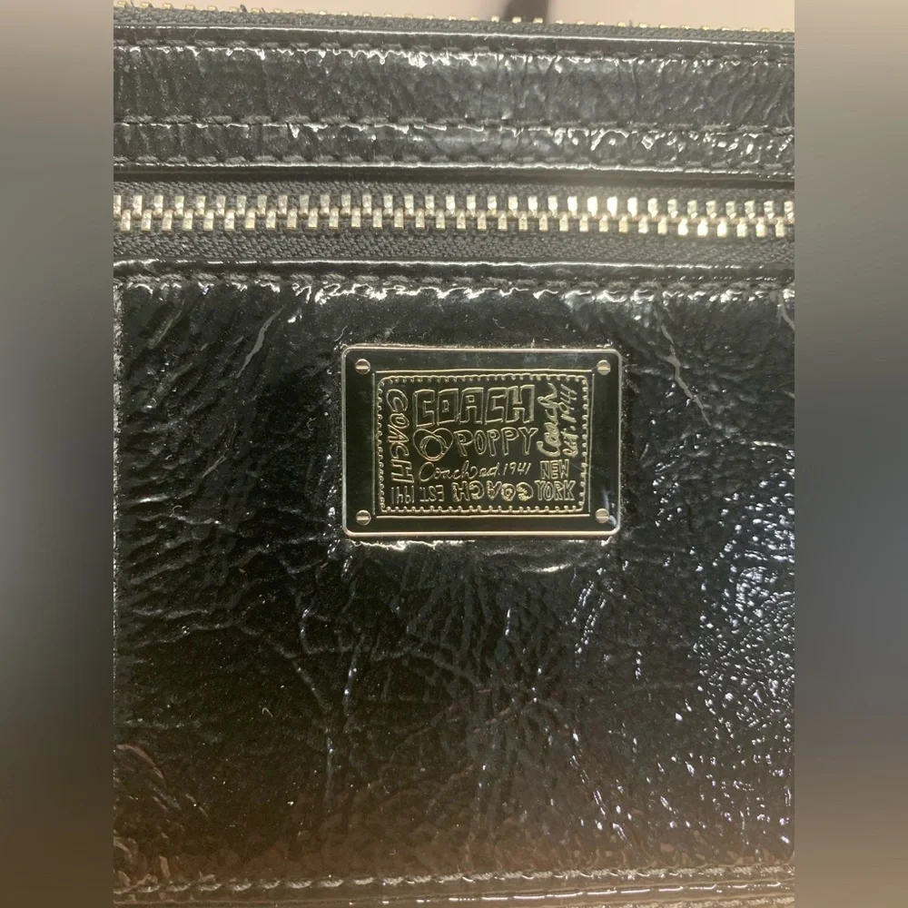 Coach Poppy Black patent leather wristlet with pink poppy interior.